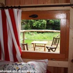 Cabane en bois en Bretagne avec vue sur la nature et mobilier extérieur en bois.