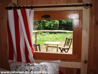 Cabane en bois en Bretagne avec vue sur la nature et mobilier extérieur en bois.
