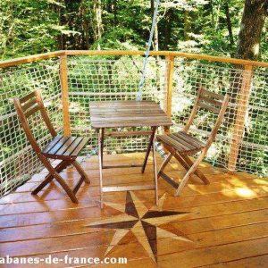Cabane perchée en Bretagne avec terrasse en bois et vue sur la forêt.