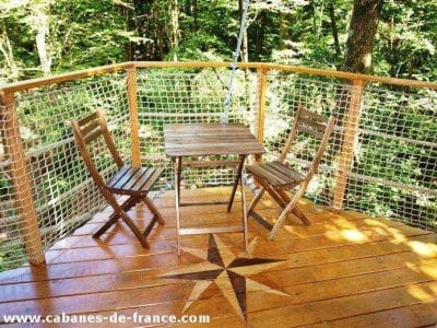 Cabane perchée en Bretagne avec terrasse en bois et vue sur la forêt.