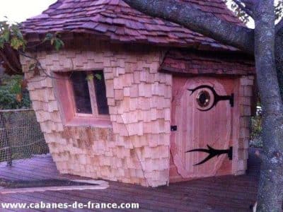 Cabane en bois originale avec un toit en bardeaux et une porte artistique.