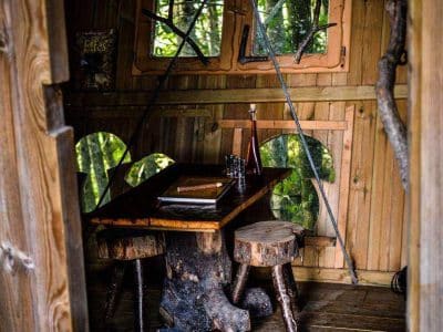 Cabane en bois en Bretagne, avec une table rustique et des chaises en troncs darbre.