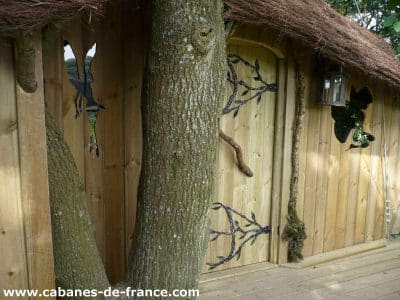 Cabane en bois en Bretagne, intégrée à un arbre avec une porte originale.