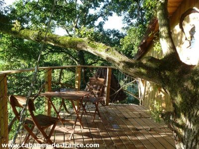 Cabane dans les arbres en Bretagne, avec terrasse en bois et vue sur la nature.