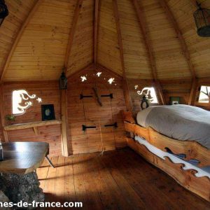 Cabane en bois en Bretagne, intérieur chaleureux avec lit en bois sculpté.