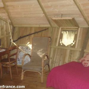 Cabane en bois en Bretagne, avec un lit confortable et une décoration chaleureuse.