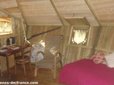 Cabane en bois en Bretagne, avec un lit confortable et une décoration chaleureuse.