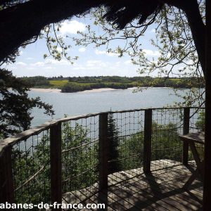 Cabane perchée en Bretagne avec vue panoramique sur un lac et la nature environnante.