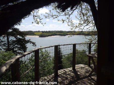 Cabane perchée en Bretagne avec vue panoramique sur un lac et la nature environnante.