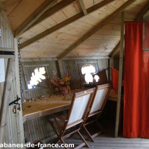 Cabane en bois en Bretagne, avec une table en bois et des fenêtres lumineuses.