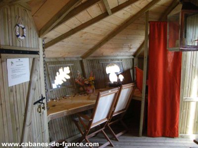 Cabane en bois en Bretagne, avec une table en bois et des fenêtres lumineuses.