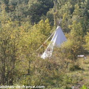 Tente tipi nichée dans la verdure, offrant un séjour insolite en Auvergne-Rhône-Alpes.