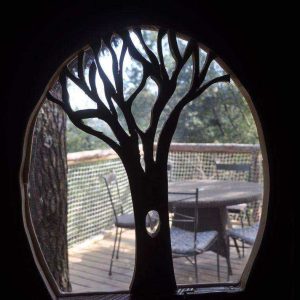 Cabane perchée en Auvergne-Rhône-Alpes avec vue sur la nature à travers une fenêtre en forme darbre.