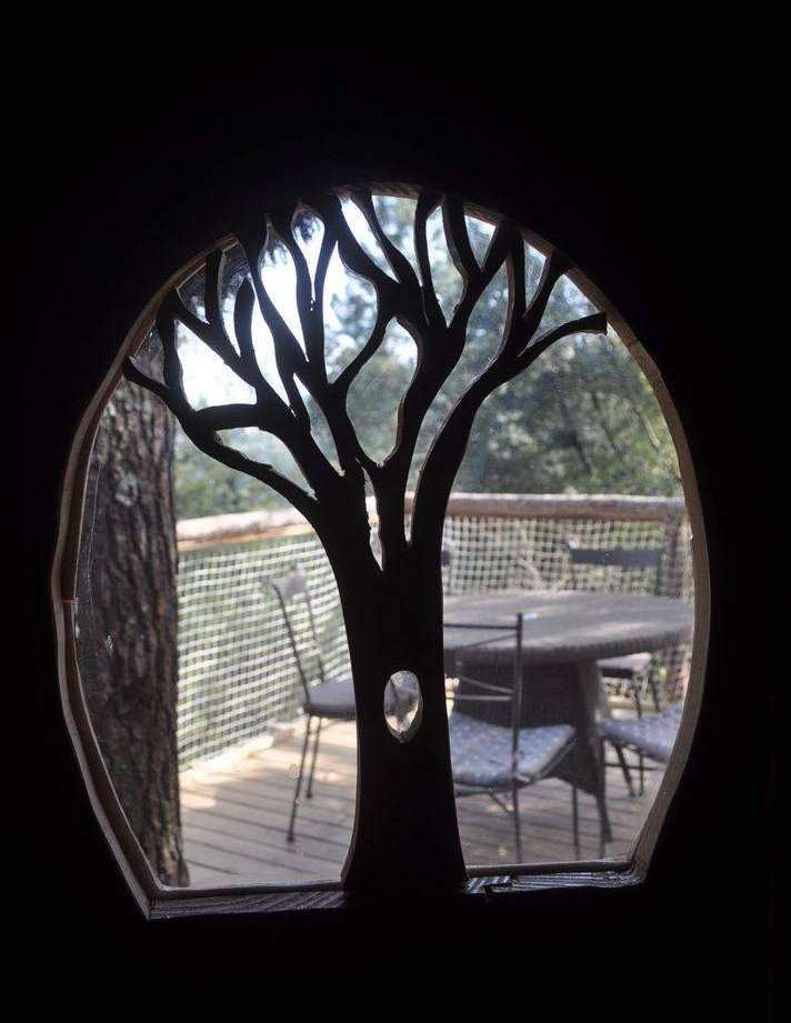 Cabane perchée en Auvergne-Rhône-Alpes avec vue sur la nature à travers une fenêtre en forme darbre.