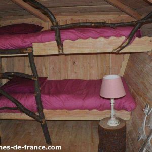 Cabane en bois avec lits superposés et décoration naturelle, ambiance chaleureuse.