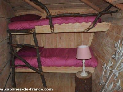 Cabane en bois avec lits superposés et décoration naturelle, ambiance chaleureuse.