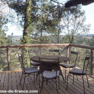 Cabane perchée en bois avec terrasse panoramique entourée darbres en Auvergne.