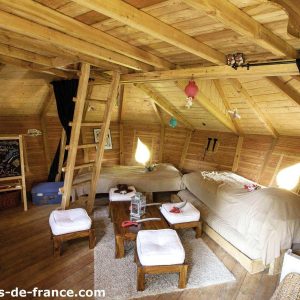 Cabane en bois à lIle-de-France, intérieur chaleureux avec lits douillets et lumière naturelle.