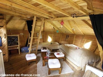 Cabane en bois à lIle-de-France, intérieur chaleureux avec lits douillets et lumière naturelle.