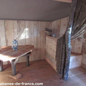Cabane en bois cosy avec table en rondins et décor naturel chaleureux.