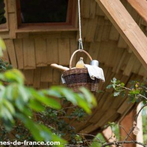 Cabane perchée dans les arbres, panier suspendu avec des douceurs à lentrée.