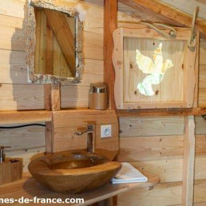 Cabane en bois avec lavabo en pierre et miroir décoratif en bois.