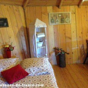 Cabane en bois cosy avec lit douillet et décor chaleureux à Languedoc-Roussillon.