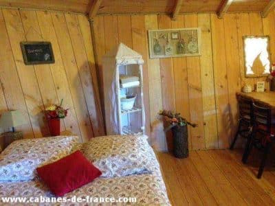 Cabane en bois cosy avec lit douillet et décor chaleureux à Languedoc-Roussillon.