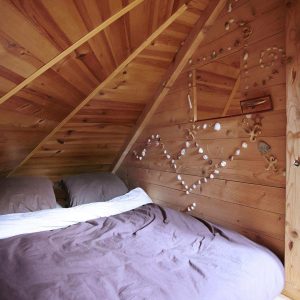 Cabane en bois cosy avec un lit douillet et des décorations en coquillages.
