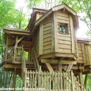 Cabane dans les arbres en Aquitaine, en bois, entourée de verdure luxuriante.