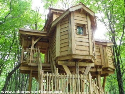 Cabane dans les arbres en Aquitaine, en bois, entourée de verdure luxuriante.