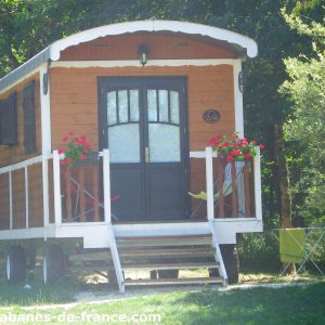 Charmante roulotte en bois avec fleurs colorées, nichée dans la verdure dAquitaine.
