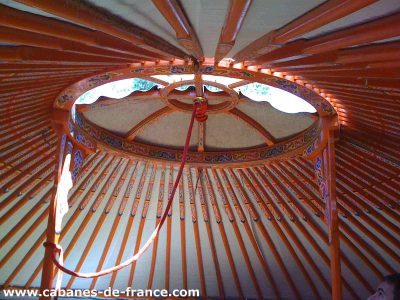 Intérieur dune yourte colorée en Auvergne-Rhône-Alpes, avec un plafond en bois décoré.