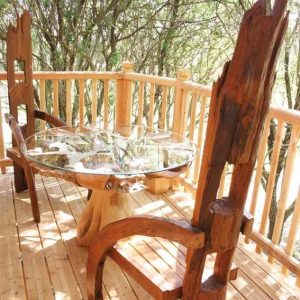 Cabane perchée en Languedoc-Roussillon avec table en bois sculpté et vue sur la nature.