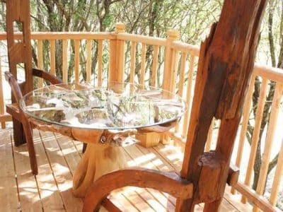 Cabane perchée en Languedoc-Roussillon avec table en bois sculpté et vue sur la nature.