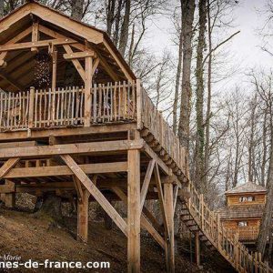 Cabane perchée en bois, entourée darbres, offrant une vue panoramique.