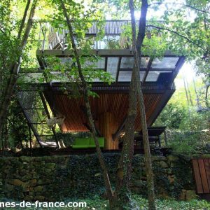Cabane perchée en bois, suspendue entre les arbres, offrant une vue sur la nature verdoyante.