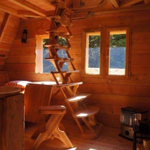 Cabane en bois chaleureuse en Auvergne, avec un escalier en bois et de grandes fenêtres.
