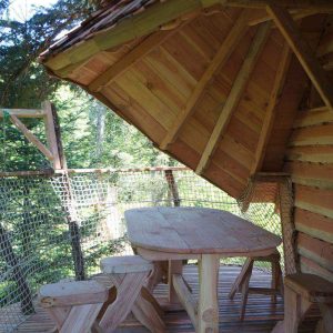 Cabane perchée en Auvergne avec terrasse en bois et vue sur la forêt.