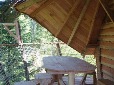 Cabane perchée en Auvergne avec terrasse en bois et vue sur la forêt.