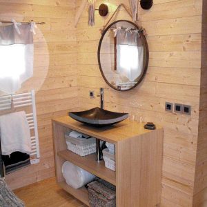 Cabane en bois dans les Pays de la Loire, avec lavabo design et miroir rond.