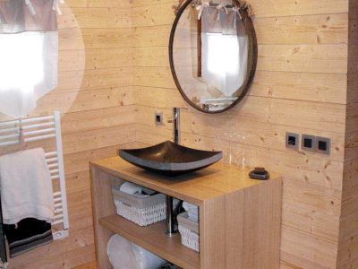 Cabane en bois dans les Pays de la Loire, avec lavabo design et miroir rond.