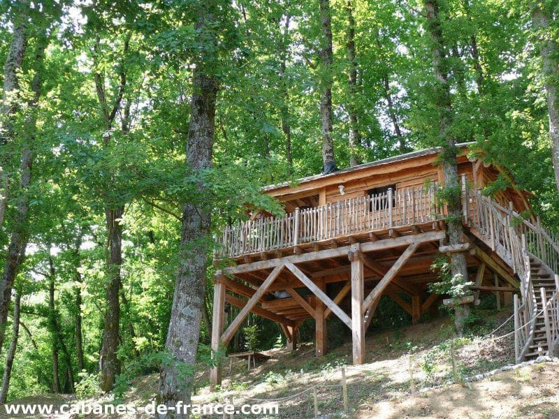 Cabane perchée en bois, entourée darbres verdoyants en Aquitaine.