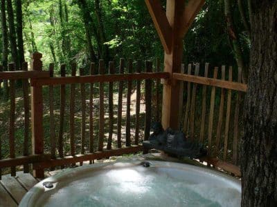 Hébergement insolite en Aquitaine avec jacuzzi en bois, entouré de verdure.