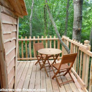 Cabane perchée en Aquitaine avec terrasse en bois et vue sur la forêt.