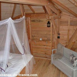 Cabane en bois en Aquitaine, avec lit à baldaquin et coin salon cosy.