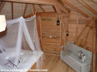 Cabane en bois en Aquitaine, avec lit à baldaquin et coin salon cosy.