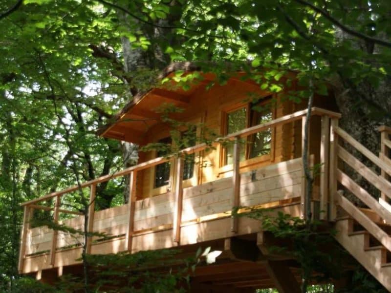 Cabane dans les arbres en Midi-Pyrénées, perchée et entourée de verdure luxuriante.