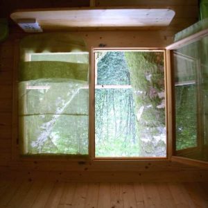 Cabane en bois avec vue sur la nature à travers une grande fenêtre.