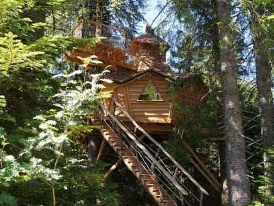 Cabane perchée en bois au cœur des arbres, offrant une vue imprenable sur la nature.